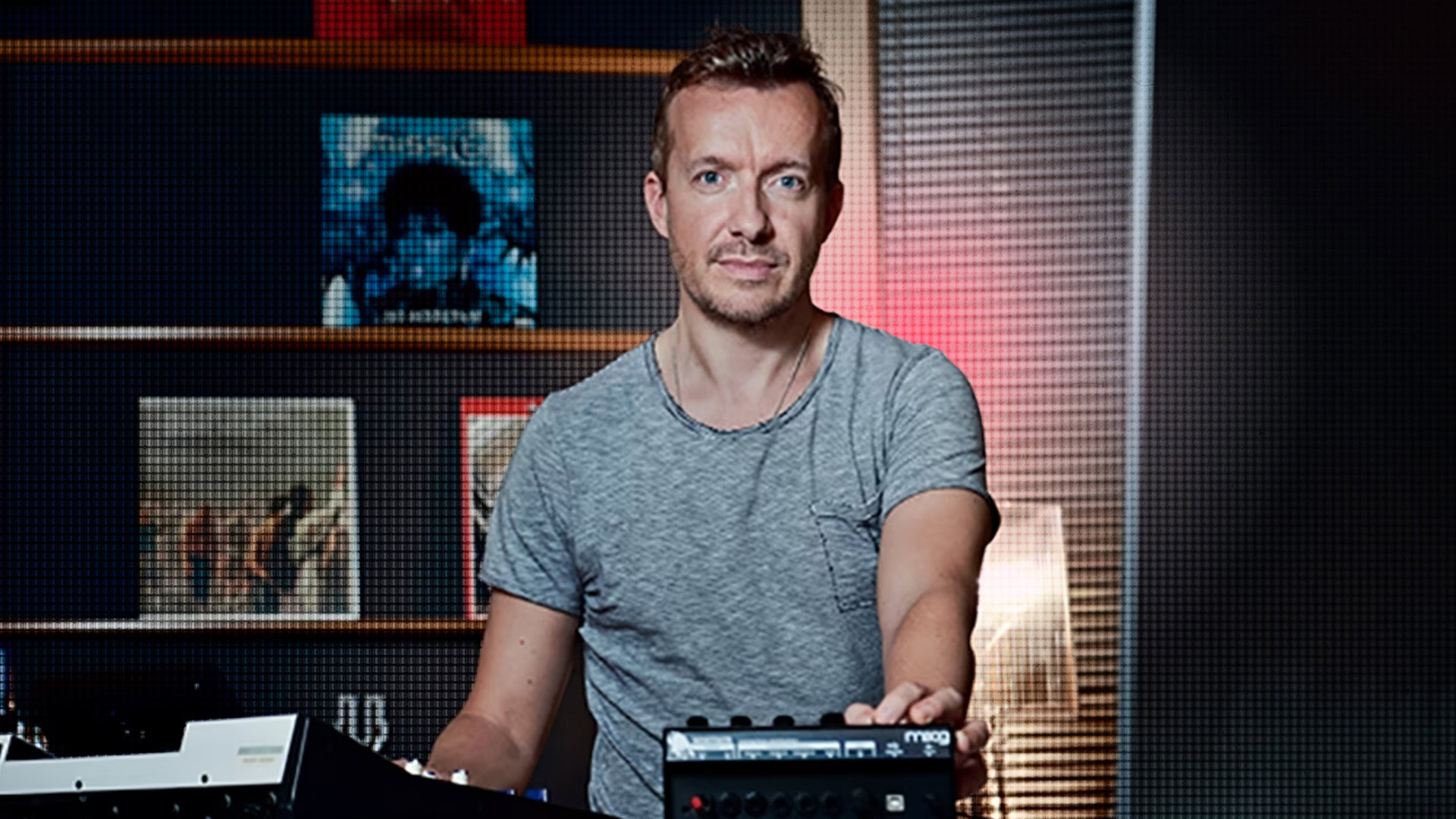 Fraser Smith in a studio with music equipment and artwork in the background.