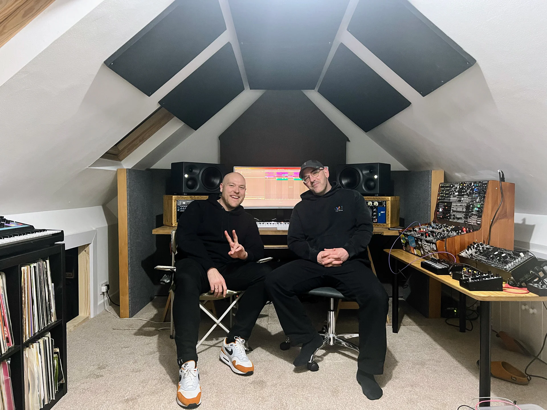 Two music producers in a professional recording studio with equipment.